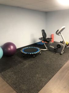 Workout area with exercise equipment including balance balls, stationary bike, trampoline