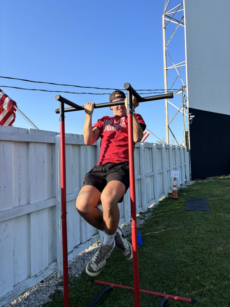 a young man uses the chin up bar on the obstacle course