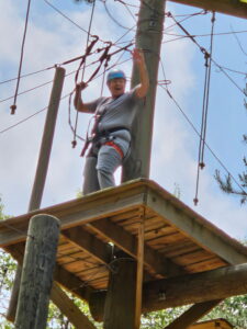 woman standing on platform on high ropes course cheering