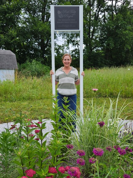 Wendy from the Madeleine Rose Foundation holding the new sign for the garden